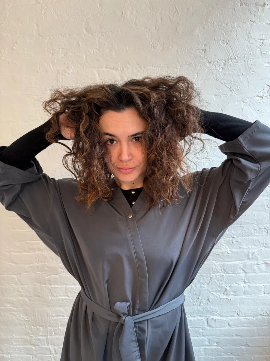 Light curly hair before a rich red bob transformation
